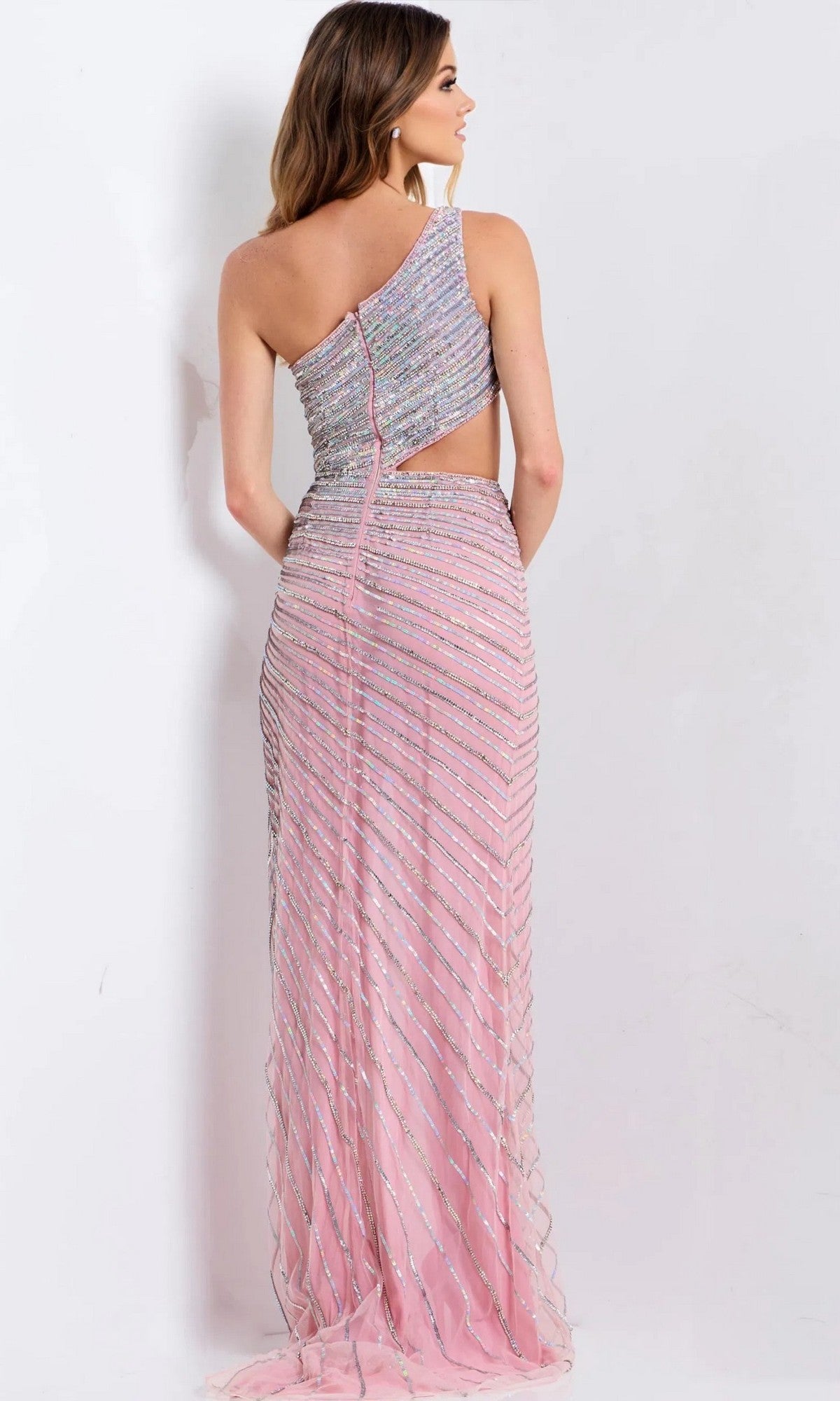 A woman models the Jovani 48563—a fitted, one-shoulder, floor-length pink prom dress with silver diagonal stripes—posing with her back to the camera against a plain background.